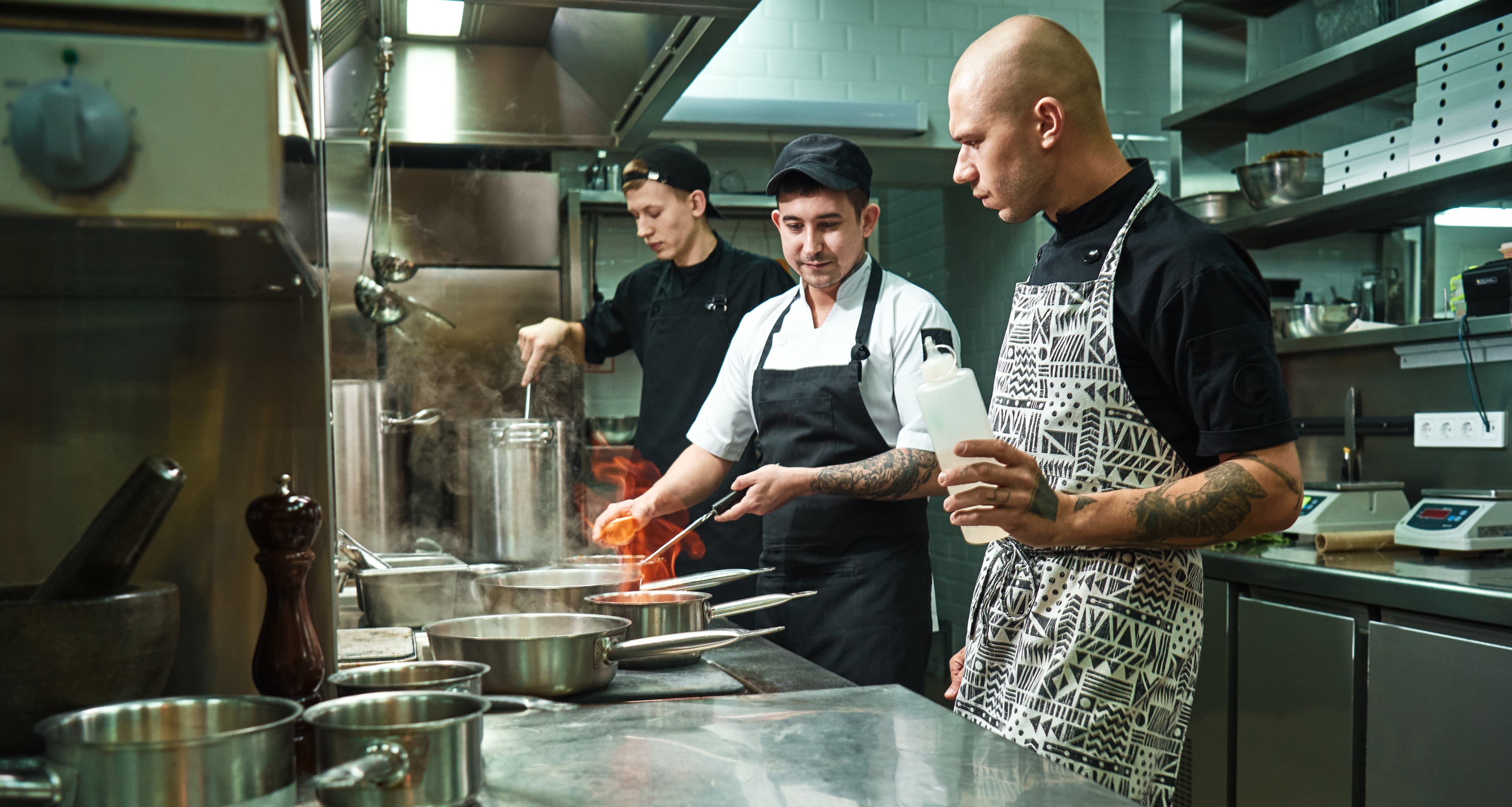 Chefs cooking together in a professional restaurant kitchen.